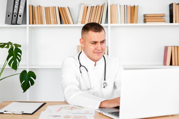 Young male doctor looking on laptop