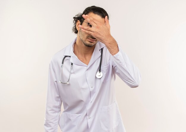 young male doctor with optical glasses wearing white robe with stethoscope covered eyes