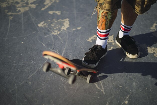 Giovane maschio facendo diversi trucchi con uno skateboard nel parco