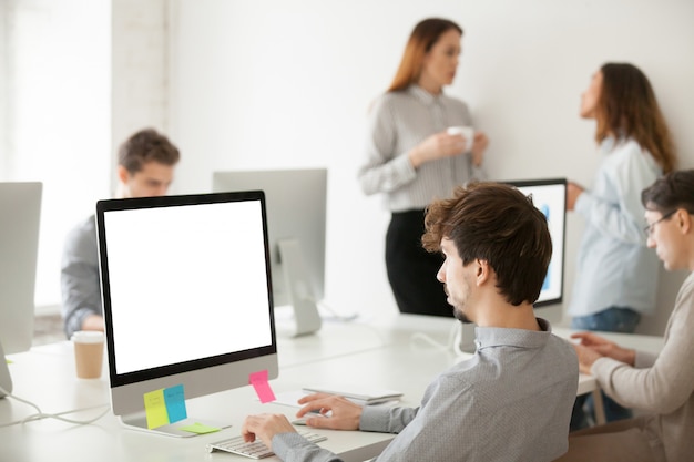 オフィスで電子メールを書くコンピューターに取り組んでいる若い男性従業員