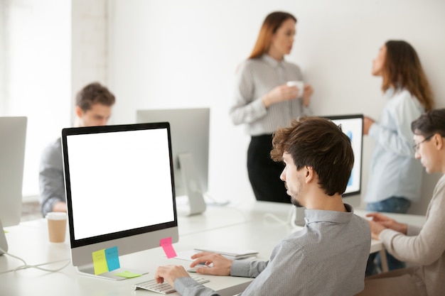 Young male employee working on computer writing email in office