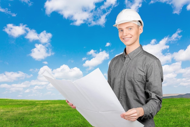 Young male engineer with helmet holding blueprint