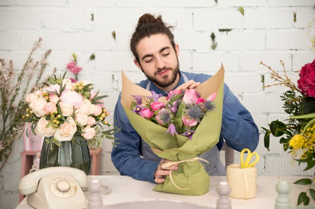 Young male florist wrapping the flower bouquet in the flower shop