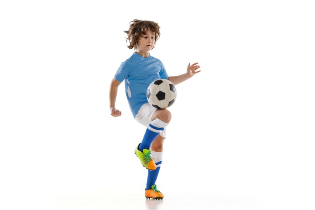 若い男性のサッカーサッカー選手の少年が白いスタジオの背景に分離されたサッカーボールでトレーニングスポーツゲーム趣味の概念