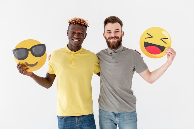 Young male friends holding emoji