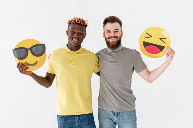 Young male friends holding emoji