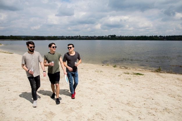 Young male friends walking with drinks