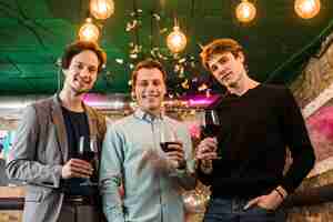 Free photo young male friends with wine glasses enjoying in party at bar