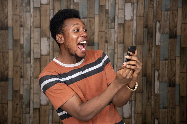 Young male getting excited over his phone while holding screaming at it joyfully