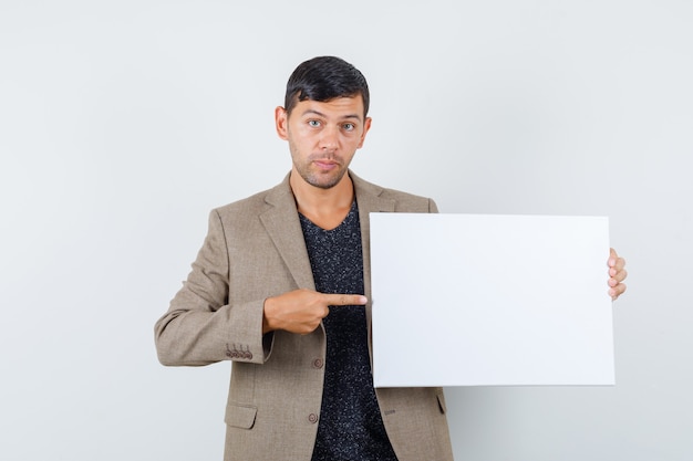 Young male in grayish brown jacket pointing to blank paper and looking focused , front view.