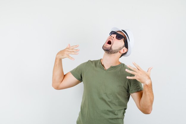 Young male in green t-shirt and hat feeling hot and looking worried