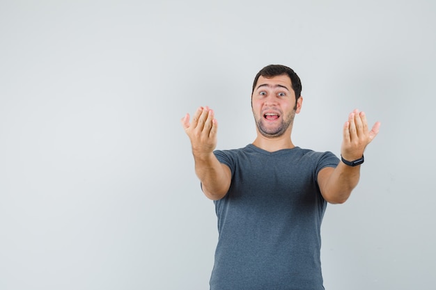 Young male in grey t-shirt inviting to come and looking excited  