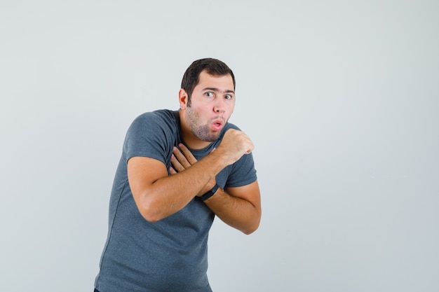 咳と病気に苦しんでいる灰色のTシャツの若い男性