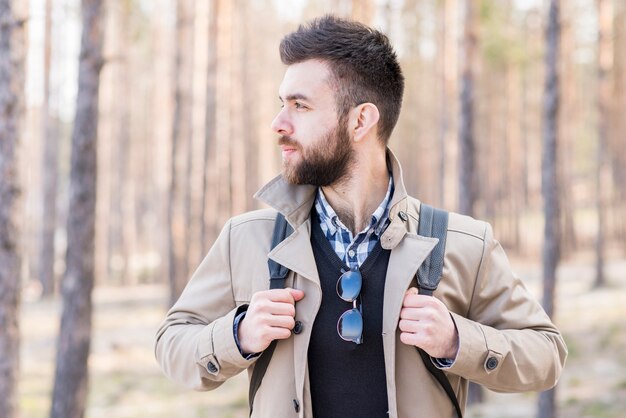 Young male hiker with his backpack looking away