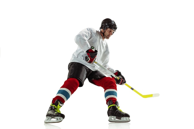 Foto gratuita giovane giocatore di hockey maschio con il bastone sul campo da ghiaccio e muro bianco