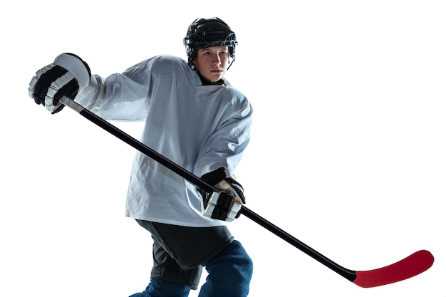 Free photo young male hockey player with the stick on ice court and white wall