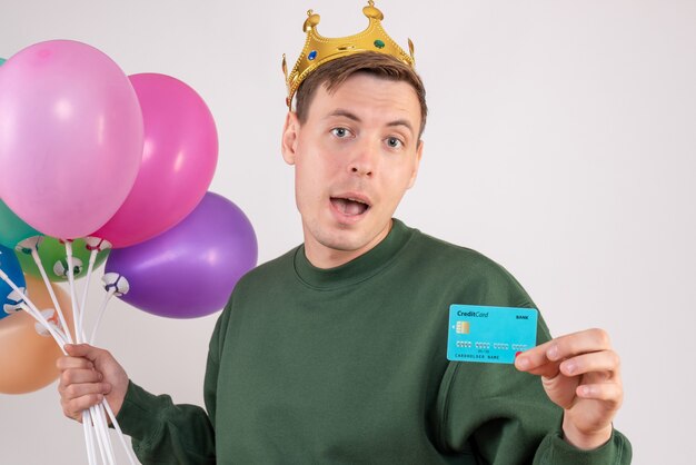 young male holding colorful balloons and bank card on white
