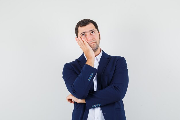 Young male holding hand on cheek in shirt