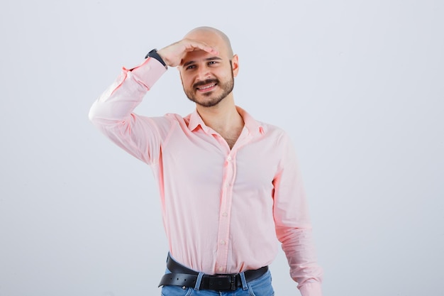 Foto gratuita giovane maschio che tiene la mano sulla fronte in camicia, jeans e sembra allegro. vista frontale.