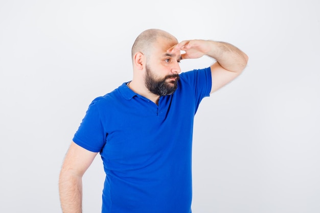 Free photo young male holding hand on forehead in t-shirt and looking wondered , front view.