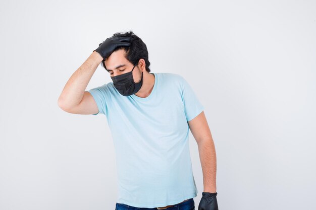 Young male holding hand on head in t-shirt and looking unwell , front view.