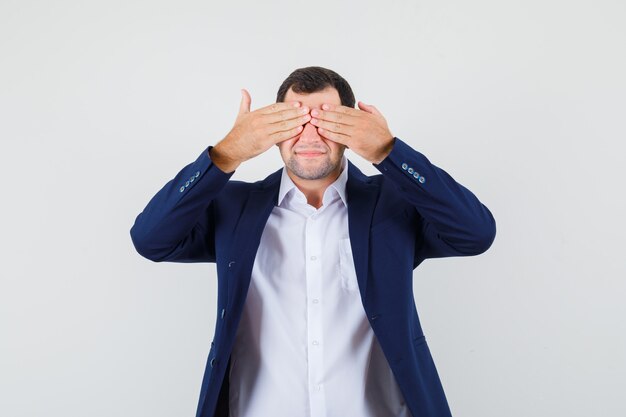 Young male holding hands on eyes in shirt