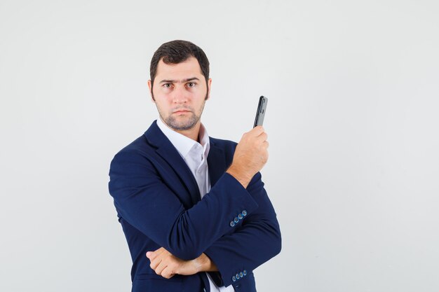 Young male holding mobile phone in shirt