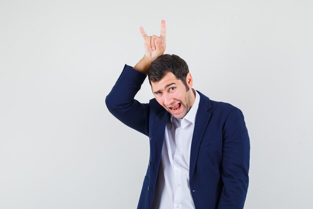 Young male holding rock symbol over head in shirt