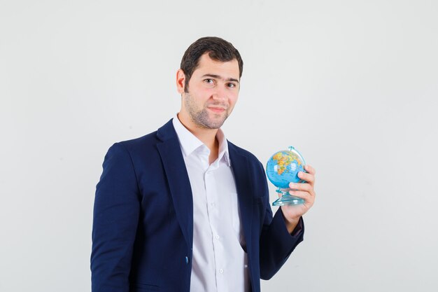 Young male holding school globe in shirt and jacket and looking confident