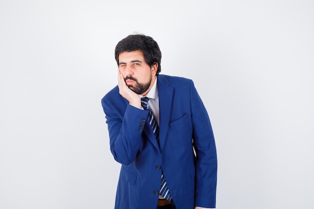 Young male leaning at his hand in shirt,jacket,tie and looking focused , front view.