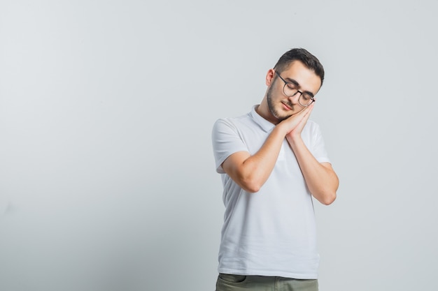 白いTシャツの枕として手のひらに寄りかかってきれいに見える若い男性