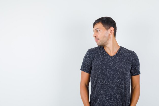 Young male looking aside in black t-shirt front view. space for text