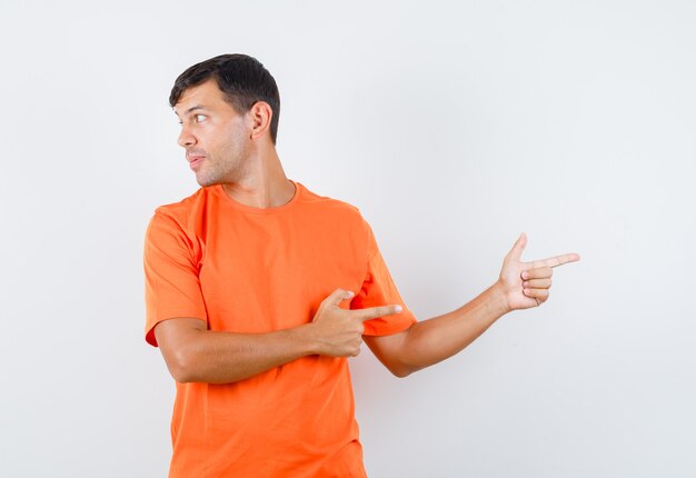オレンジ色のTシャツを指差して、焦点を合わせて見ながら脇を見て若い男性