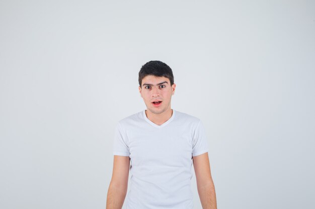 Young male looking at camera in t-shirt and looking perplexed , front view.