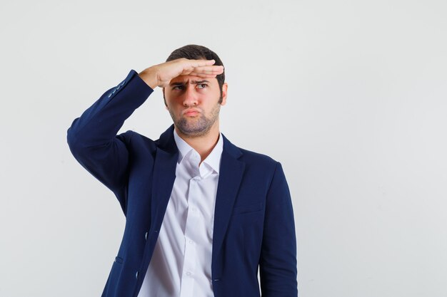 Young male looking far away with hand over head in shirt, jacket and looking pensive