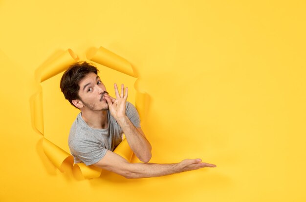 Young male looking from torn yellow paper background sale indoor guy