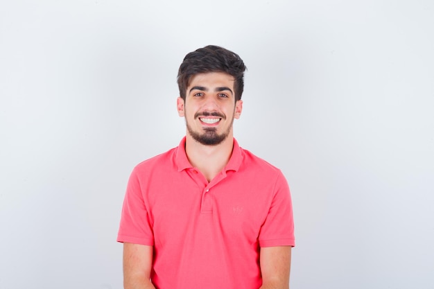 Young male looking in pink t-shirt and looking cheerful , front view.