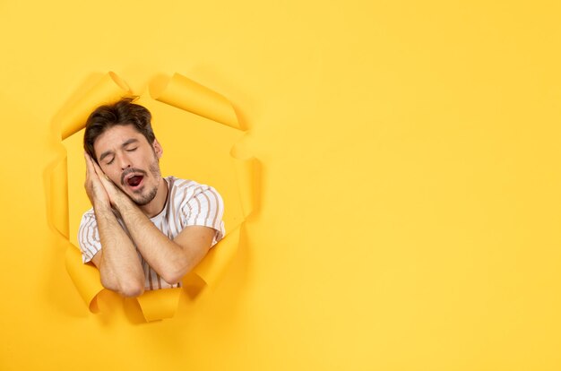 Young male looking and standing on the torn yellow paper background guy indoor sale facial