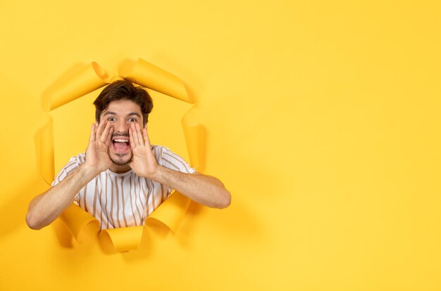 Young male looking and standing on torn yellow paper surface guy sale indoor facial