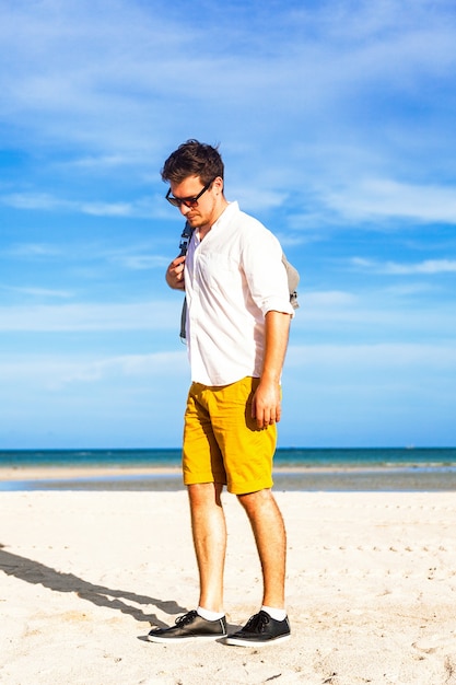 スタイリッシュなバックパックで海のそばで夏休みを楽しむ若い男性モデル