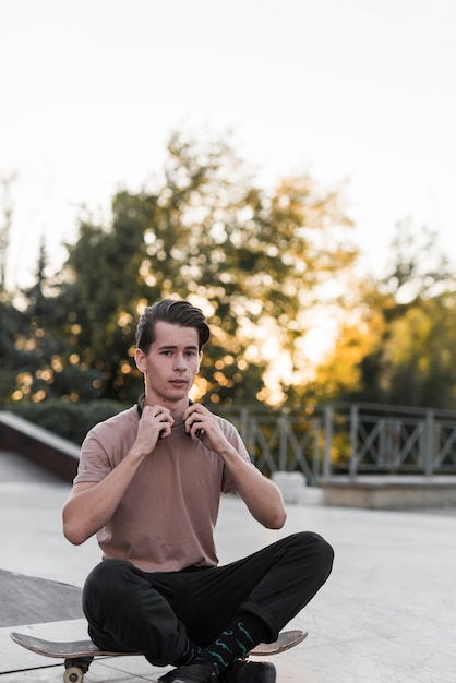 Young male model sitting on skateboard