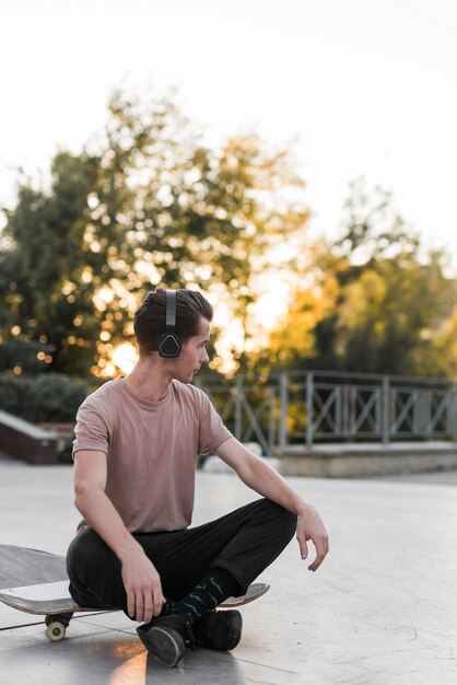 Young male model sitting on skateboard