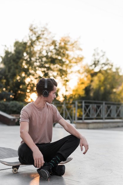 Young male model sitting on skateboard