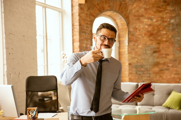 Young male office worker drinking coffee at the office