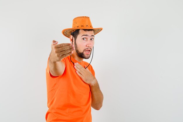オレンジ色のTシャツを着た若い男性、来てくれる帽子、正面図。