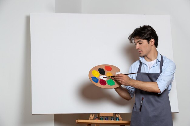 Young male painter inside studio with color paints in his hands white background art drawing