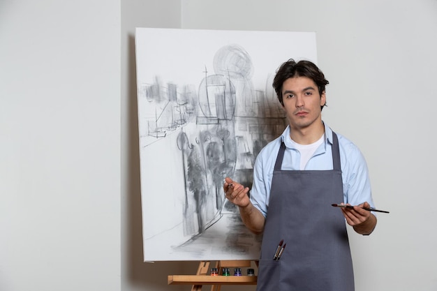 Молодой художник-мужчина с черно-белой студией рисования на белом фоне