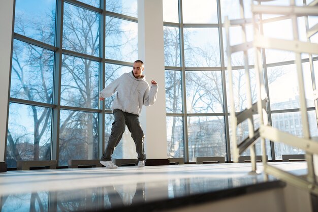 Young male performer dancing in a building with big windows