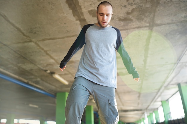 Free photo young male performer dancing in a parking lot with pilons