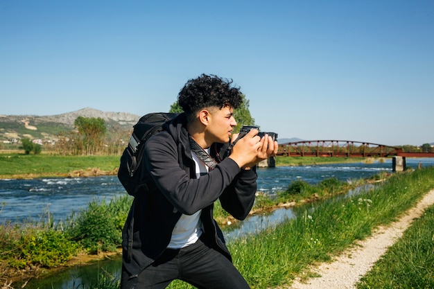 Young male photographer photographing nature on summer day